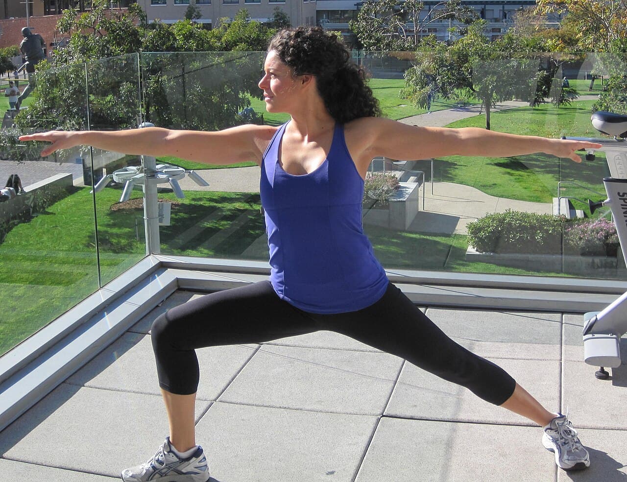 Woman in a wide stance with front knee bent and arms stretched out to the sides in Warrior II
